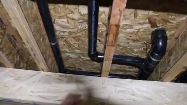 Black pvc basement drain rough in between joists, seen during drain cleaning service in Chino Valley, AZ.