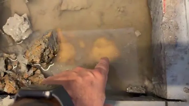 Hand pointing at concrete slab leak, during slab leak work for a Chino Valley, AZ property.