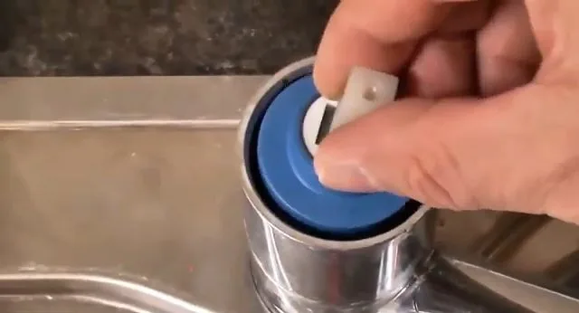 Lifting cartridge cap from kitchen faucet, during a faucet repair call in Chino Valley, AZ.