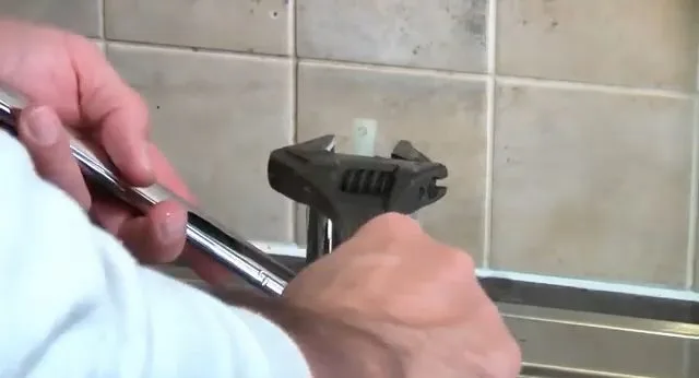 Loosening kitchen faucet handle with wrench, seen during faucet repair service in Chino Valley, AZ.