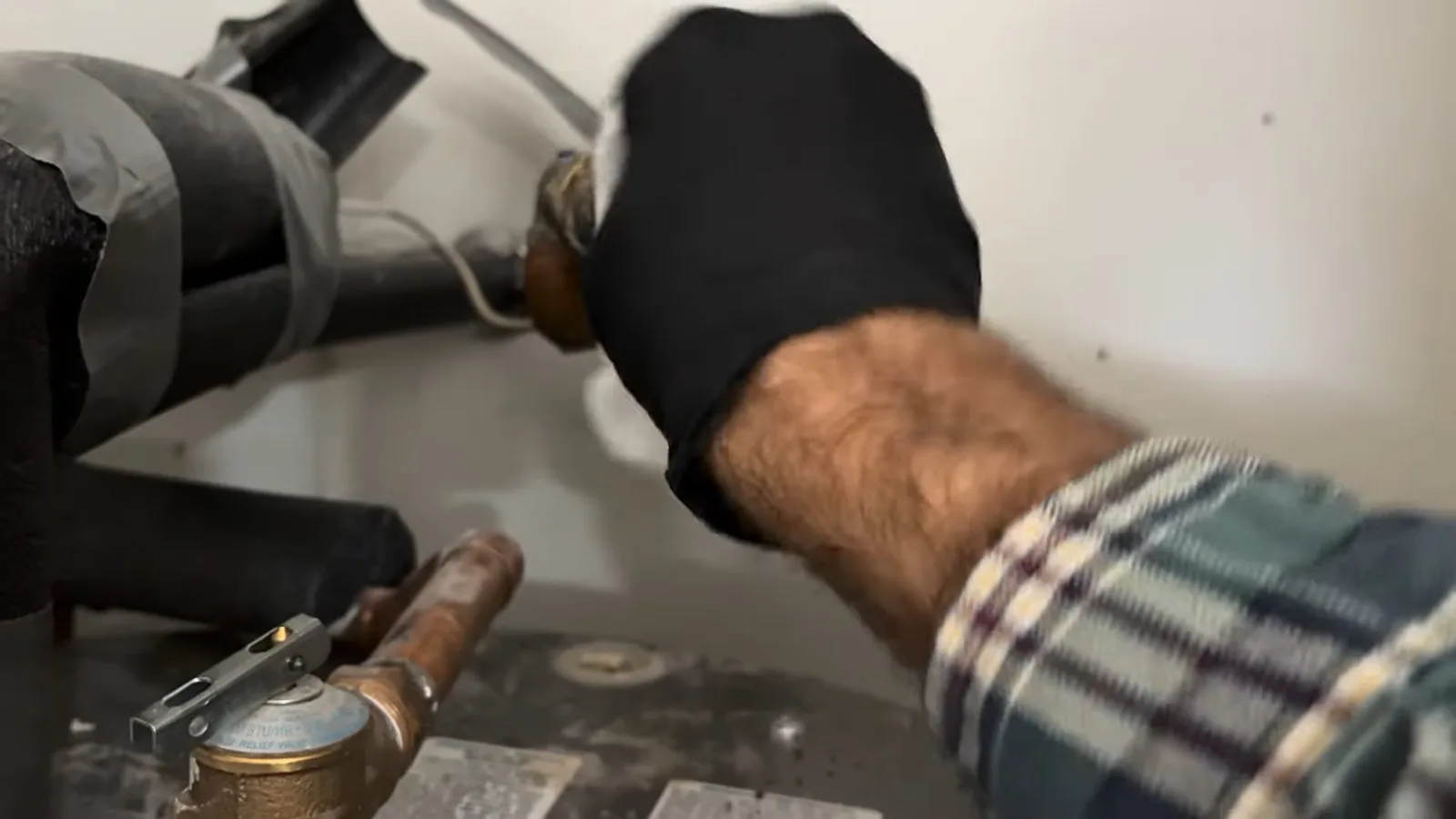 Technician fixing water heater inlet hose, photographed during water heater work in Chino Valley, AZ.