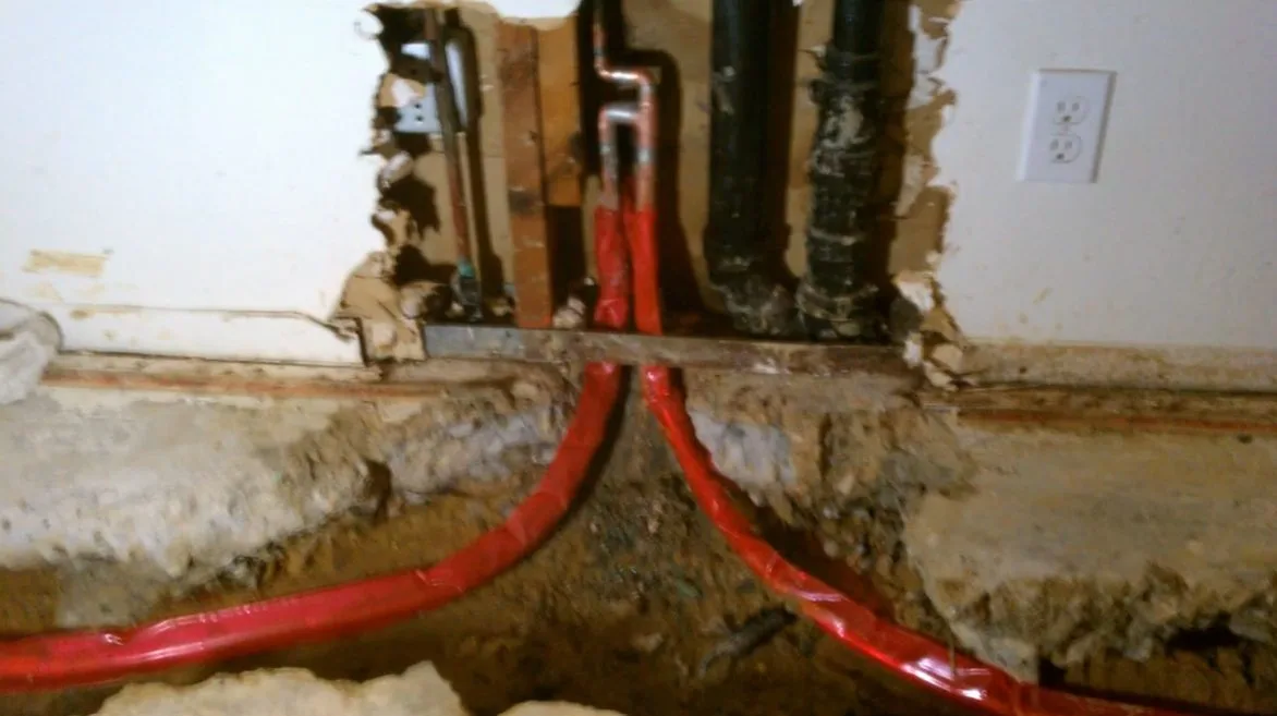 Water heater pipes beneath open wall, photographed during water heater work in Chino Valley, AZ.