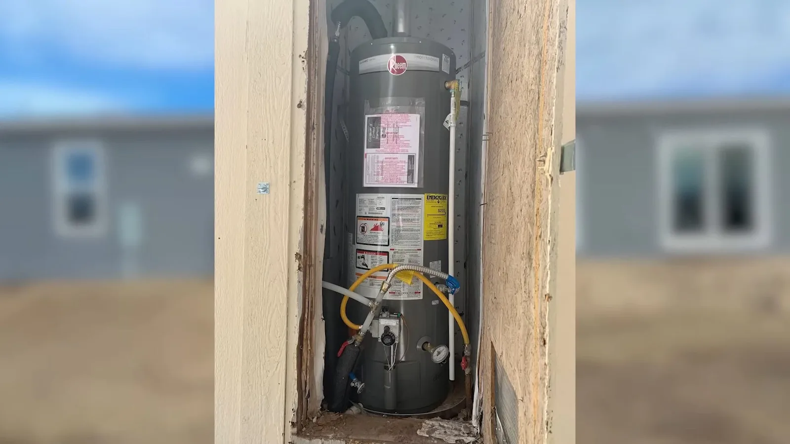 Water heater visible through wall opening, photographed during water heater work in Chino Valley, AZ.