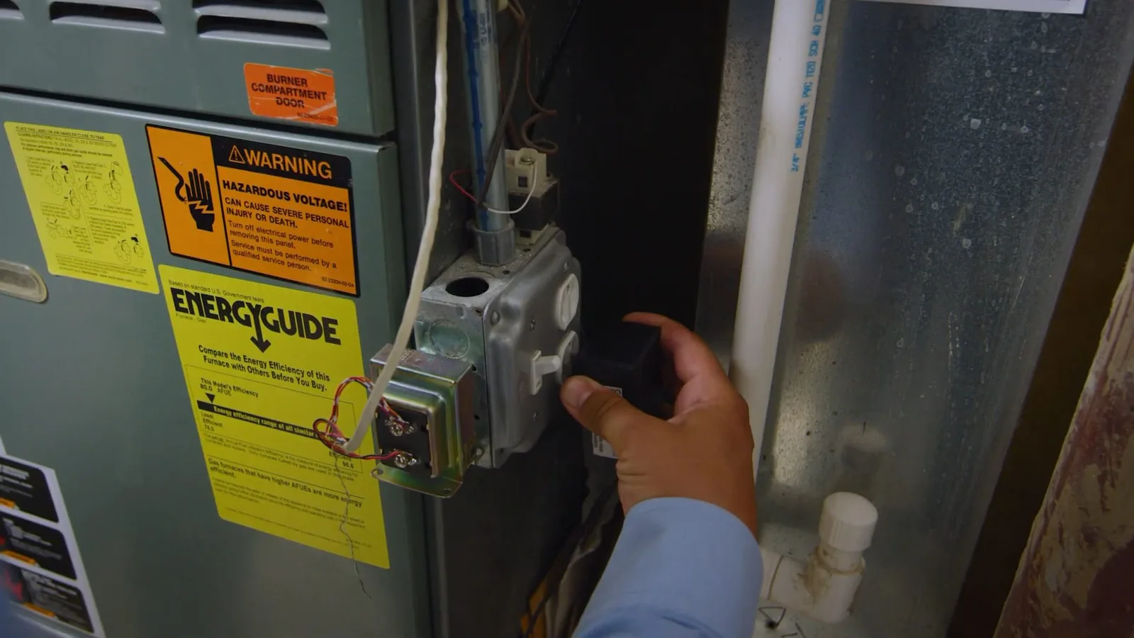 Worker checking water heater control panel, during water heater work for a Chino Valley, AZ property.