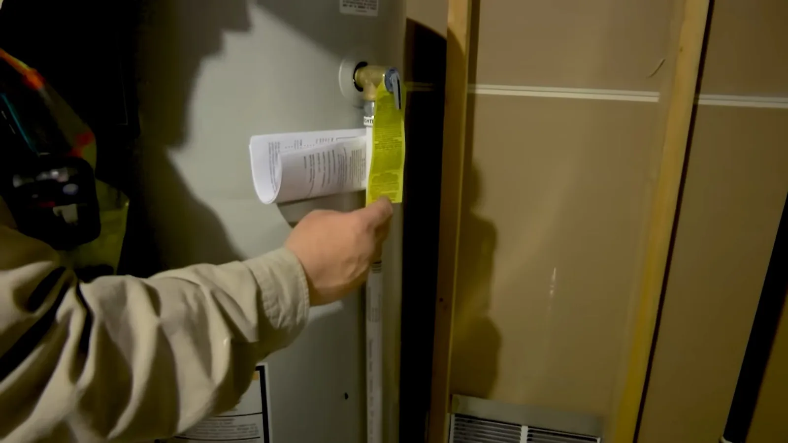 Worker checking water heater wall panel, photographed during water heater work in Chino Valley, AZ.
