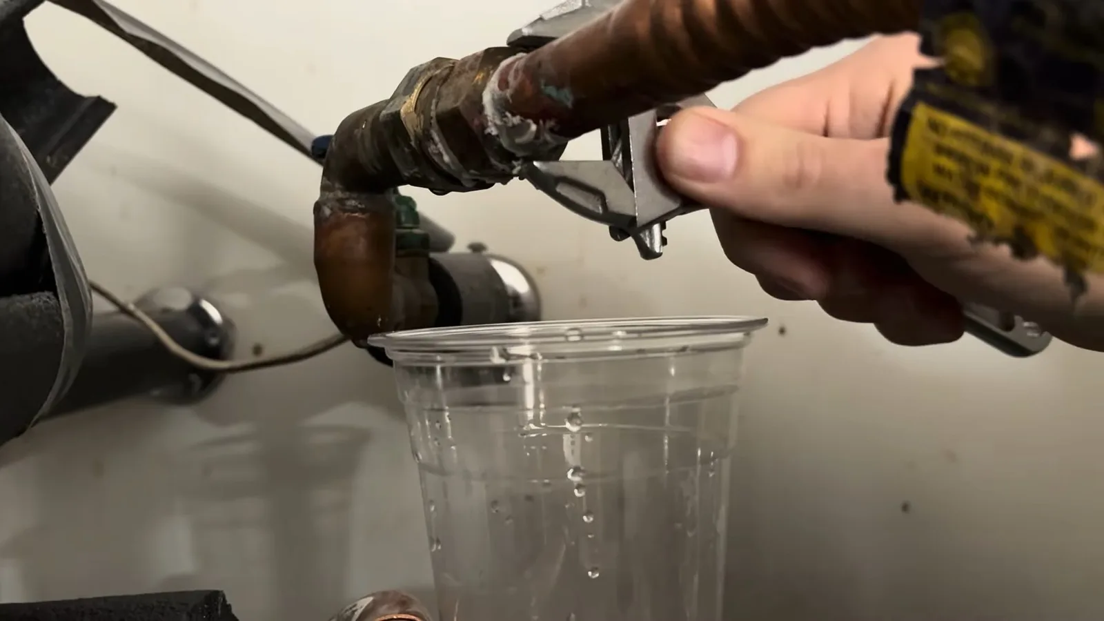 Worker loosening water heater inlet fitting, captured on a water heater job near Chino Valley, AZ.