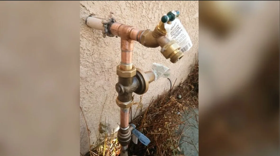 Worker opening water heater shutoff valve, photographed during water heater work in Chino Valley, AZ.